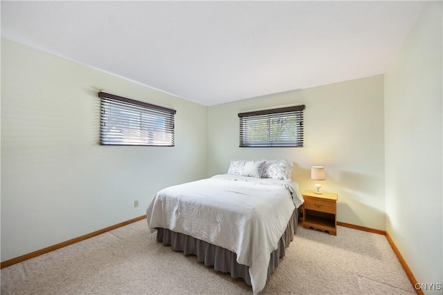 bedroom with light colored carpet and baseboards