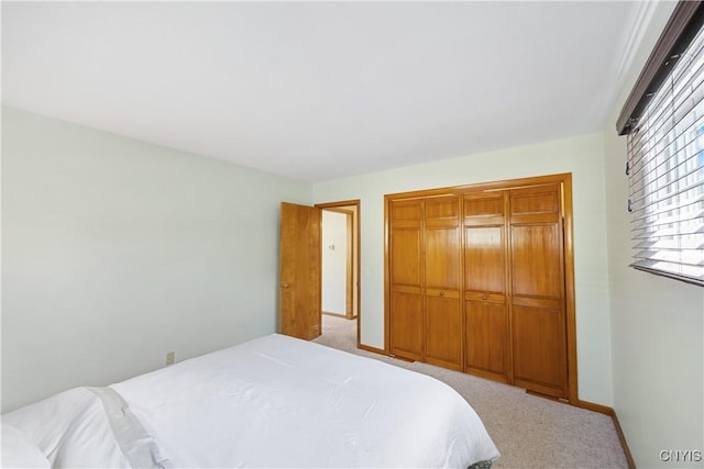 bedroom with baseboards, light colored carpet, and a closet