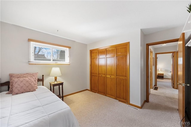 bedroom with light colored carpet, baseboards, visible vents, and a closet