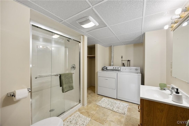 bathroom featuring washer and dryer, a shower stall, a paneled ceiling, and vanity