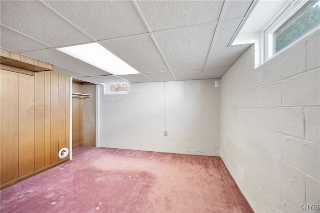 below grade area with carpet floors, a paneled ceiling, and concrete block wall