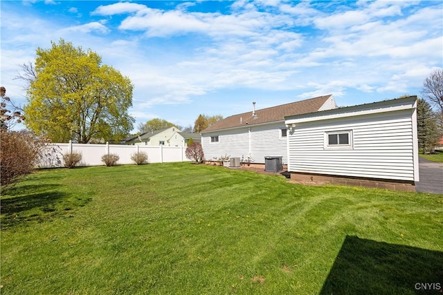 back of house featuring fence, central AC unit, and a lawn