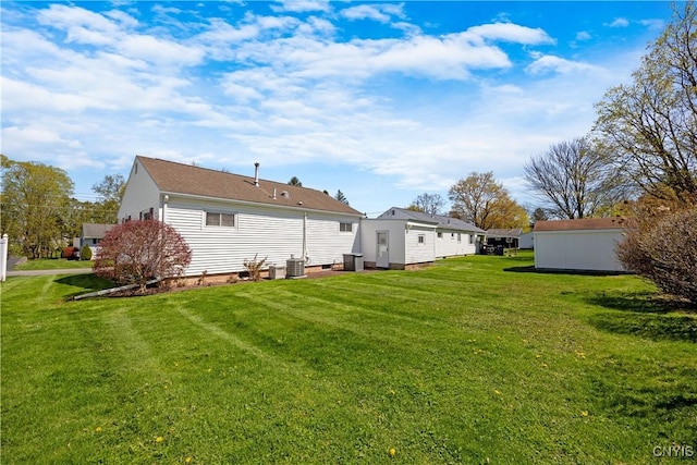 rear view of property featuring a lawn and central air condition unit
