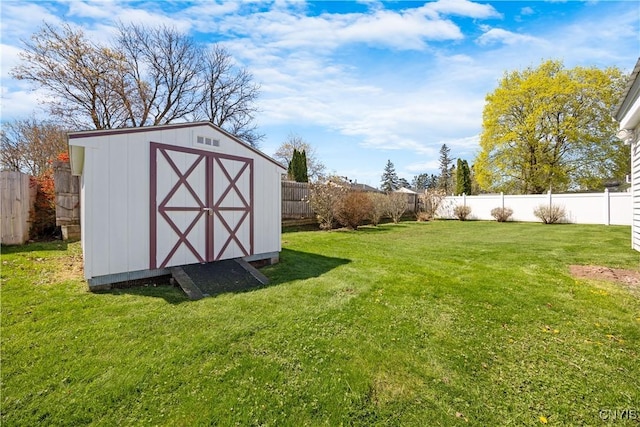 view of yard with a storage unit, a fenced backyard, and an outbuilding