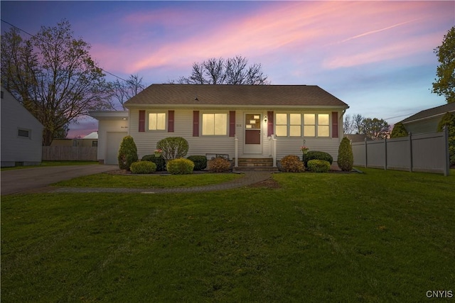 bungalow-style house with fence, an attached garage, driveway, and a front lawn