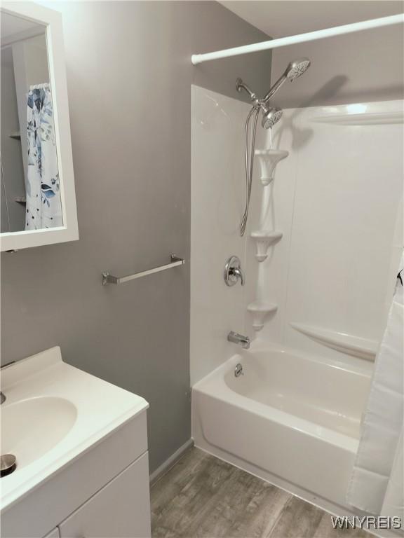 full bath featuring shower / bath combo with shower curtain, wood finished floors, and vanity