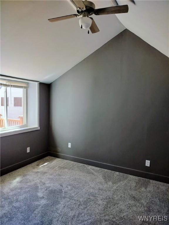 carpeted spare room with baseboards, a ceiling fan, and lofted ceiling