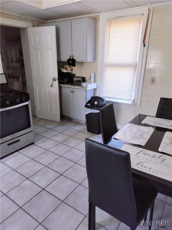 kitchen featuring stainless steel range with gas stovetop, gray cabinetry, and light tile patterned floors