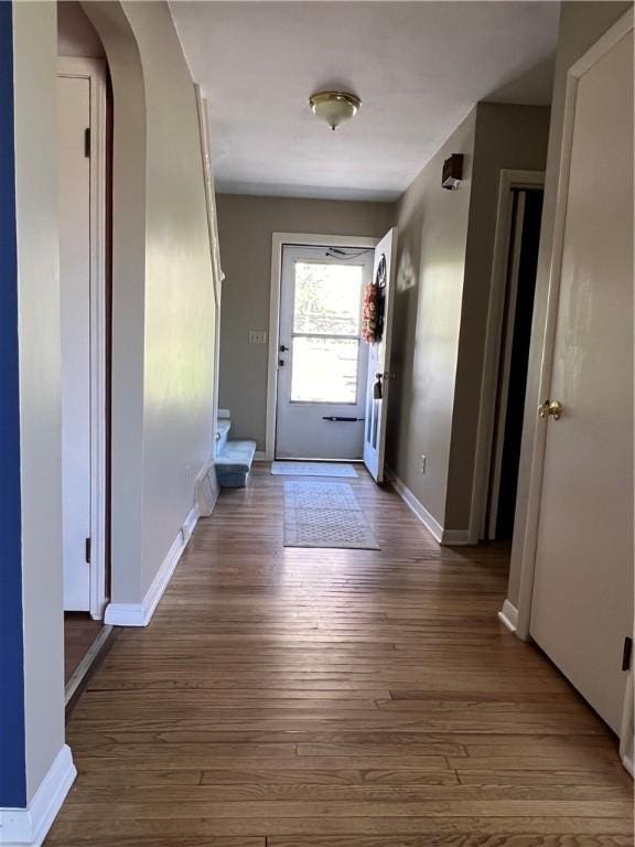 entryway with baseboards, arched walkways, and dark wood-style floors