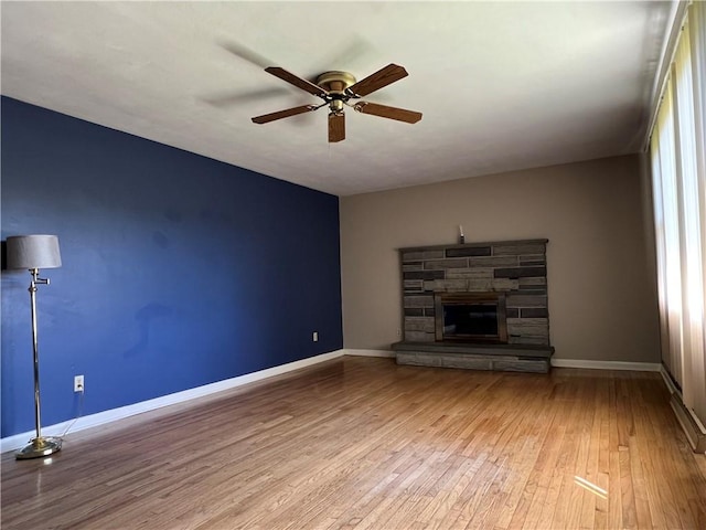 unfurnished living room featuring baseboards, a ceiling fan, a fireplace, and hardwood / wood-style flooring