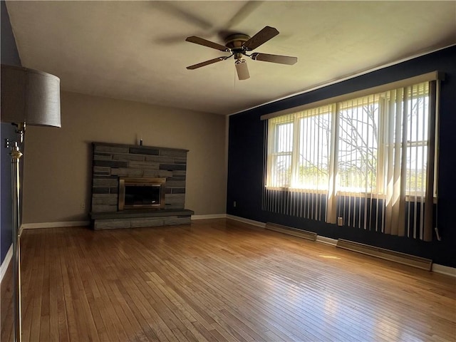unfurnished living room featuring wood-type flooring, a fireplace, baseboards, ceiling fan, and a baseboard radiator