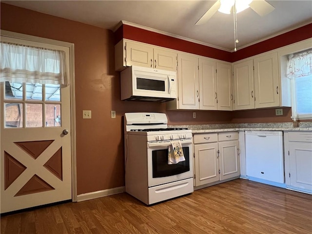 kitchen featuring plenty of natural light, white appliances, wood finished floors, and white cabinetry