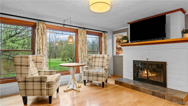 sitting room with a brick fireplace and wood finished floors
