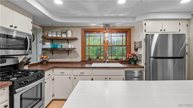 kitchen with stainless steel appliances, recessed lighting, white cabinetry, and a sink