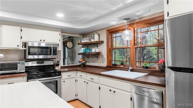 kitchen featuring a toaster, white cabinetry, a sink, appliances with stainless steel finishes, and backsplash