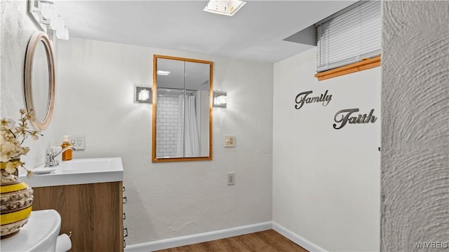 bathroom featuring baseboards, vanity, toilet, and wood finished floors