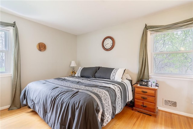 bedroom featuring baseboards, visible vents, and wood finished floors