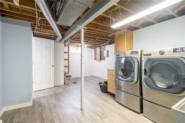laundry room with light wood-style floors, cabinet space, and washer and dryer