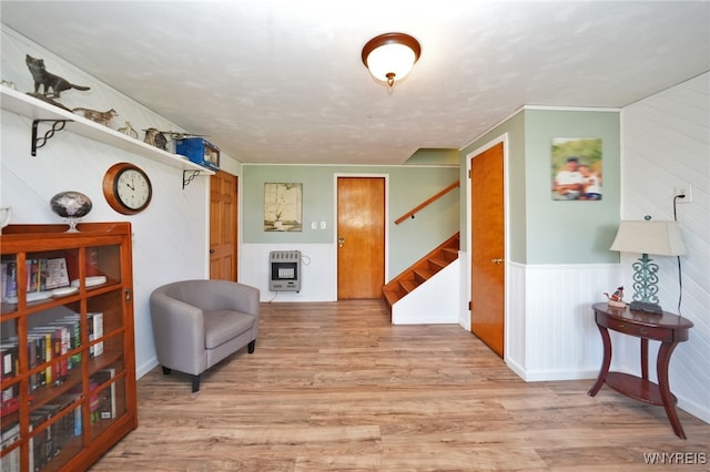 sitting room with heating unit, wood finished floors, and stairway