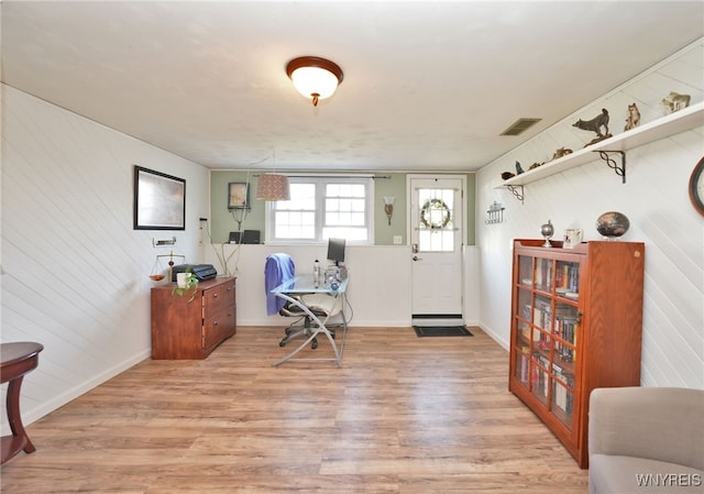 foyer entrance featuring wooden walls, baseboards, light wood-style flooring, and visible vents