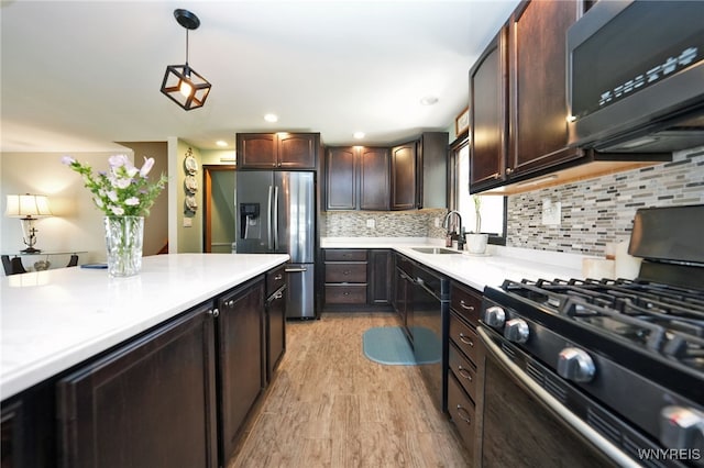 kitchen with dark brown cabinets, a sink, light countertops, stainless steel refrigerator with ice dispenser, and gas range oven