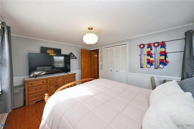 bedroom featuring a closet, ornamental molding, wainscoting, and wood finished floors