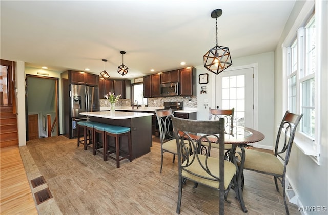 dining room featuring light wood-style floors, recessed lighting, and stairs