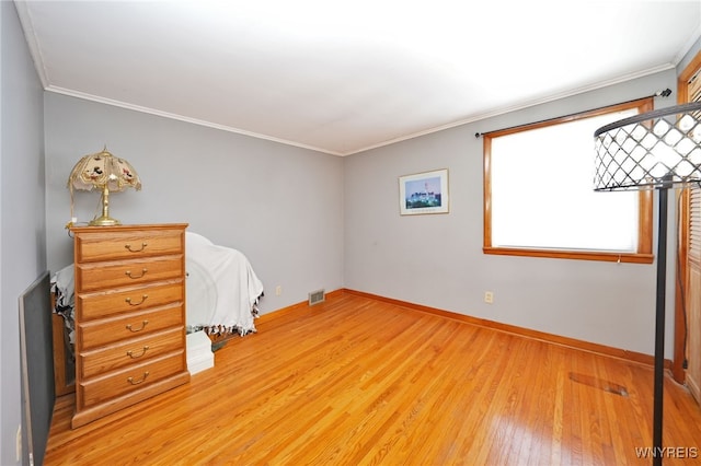 bedroom featuring baseboards, visible vents, ornamental molding, and light wood-style floors