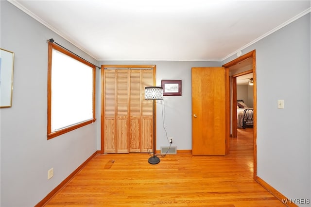 interior space with light wood-style floors, baseboards, ornamental molding, and visible vents