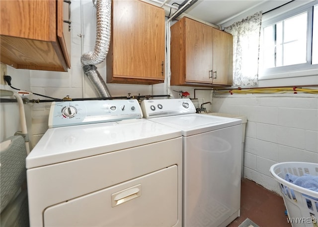laundry area with cabinet space, concrete block wall, and washing machine and dryer