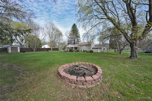 view of yard featuring fence, an outbuilding, a fire pit, and a shed