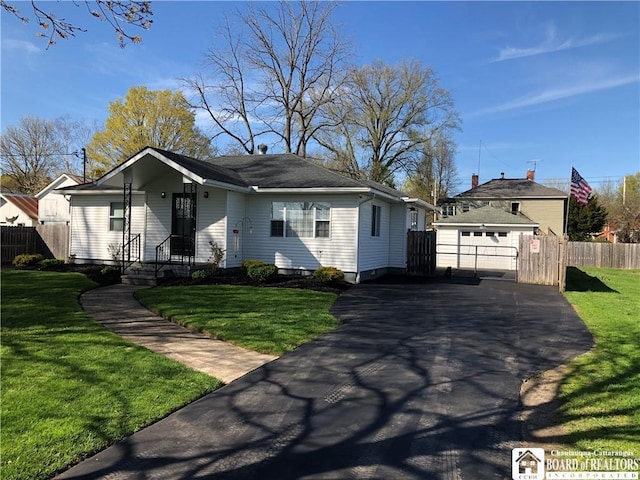 view of front facade with an outdoor structure, a garage, fence, a front yard, and driveway