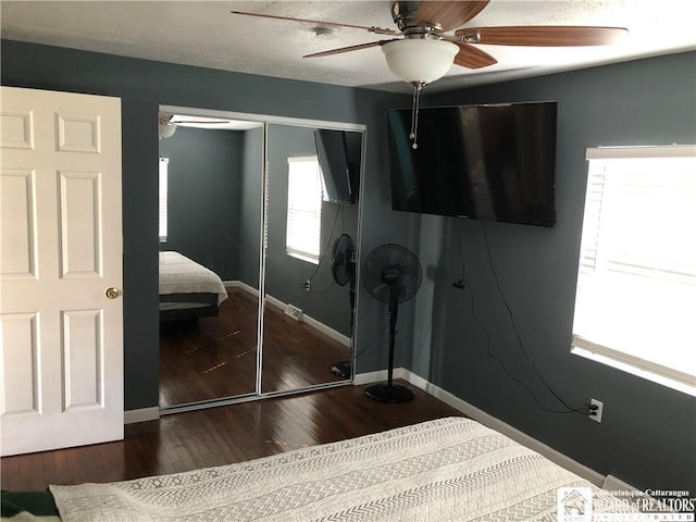 bedroom with baseboards, ceiling fan, a closet, and dark wood-type flooring