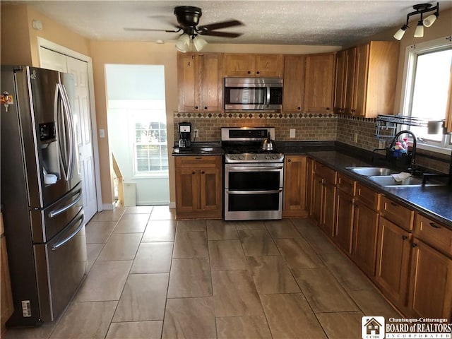 kitchen with a sink, appliances with stainless steel finishes, dark countertops, and tasteful backsplash