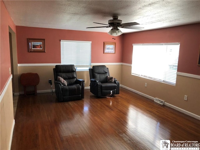 sitting room featuring visible vents, plenty of natural light, ceiling fan, and wood finished floors
