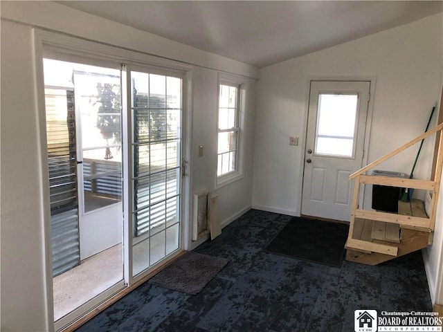 doorway with baseboards, vaulted ceiling, and carpet