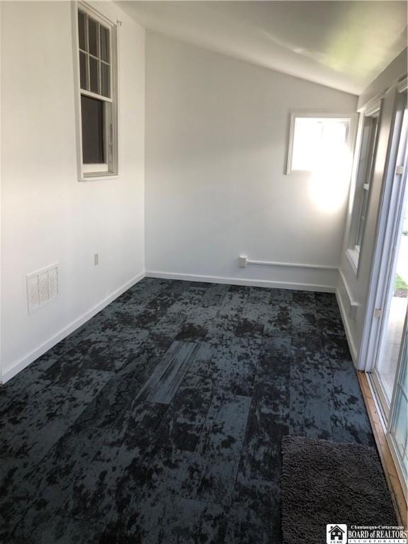 unfurnished room with carpet floors, baseboards, vaulted ceiling, and a healthy amount of sunlight