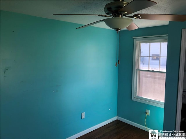 spare room with a ceiling fan, baseboards, and dark wood finished floors