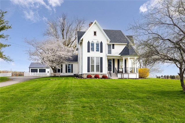 view of front facade featuring aphalt driveway, a garage, an outbuilding, a chimney, and covered porch