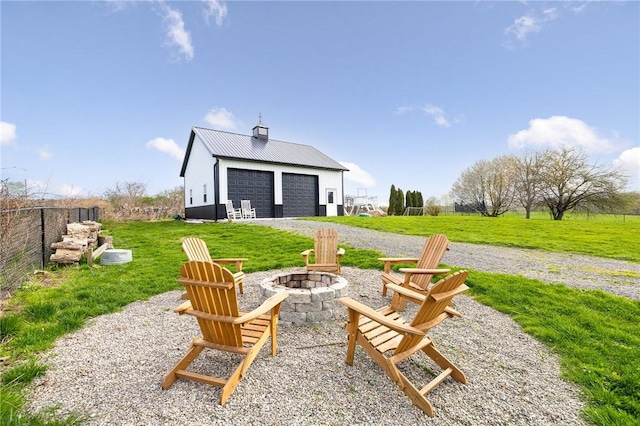exterior space with a garage, a fire pit, and an outbuilding