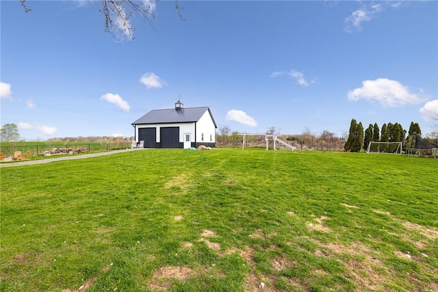 view of yard featuring a detached garage, fence, and an outdoor structure