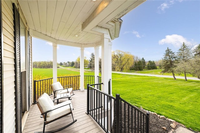 wooden terrace featuring a lawn, a rural view, and a porch