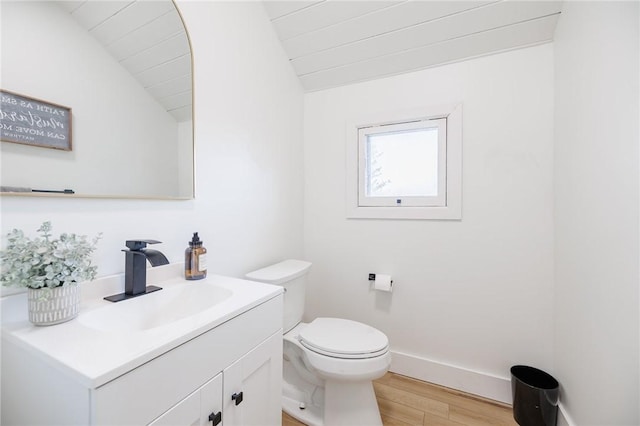 bathroom featuring vaulted ceiling, wood finished floors, vanity, baseboards, and toilet