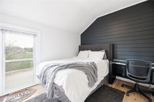 bedroom with wooden walls, vaulted ceiling, and wood finished floors