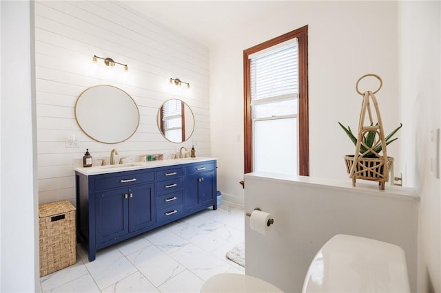 full bathroom featuring double vanity, toilet, a sink, and marble finish floor