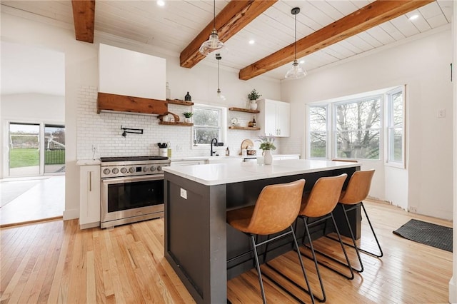 kitchen with open shelves, stainless steel range with electric cooktop, light countertops, white cabinets, and light wood finished floors