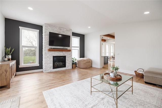 living area featuring light wood-style floors, baseboards, vaulted ceiling, and a fireplace
