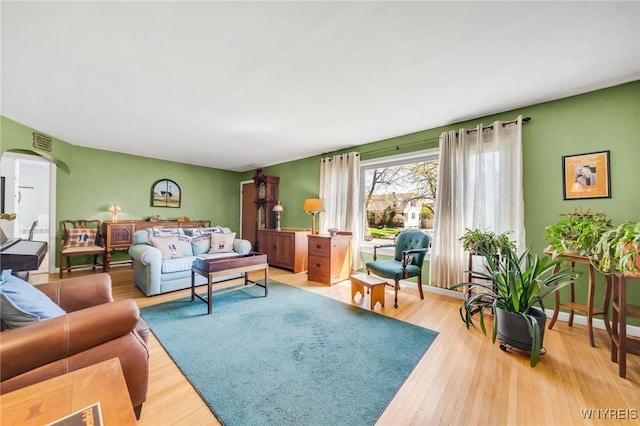 living area featuring arched walkways, wood finished floors, and visible vents