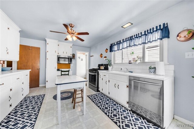 kitchen with ceiling fan, appliances with stainless steel finishes, a sink, white cabinetry, and light floors