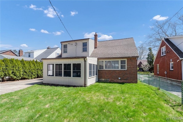 rear view of property featuring a lawn, fence, a chimney, and board and batten siding